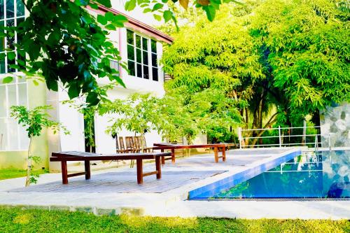 阿努拉德普勒Shanthi Villa Resort的游泳池旁的野餐桌和长凳