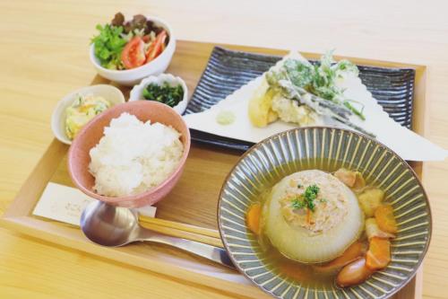 对马市Guest House「さごんヴィレッジ」的盘子里放着米饭和蔬菜的食物