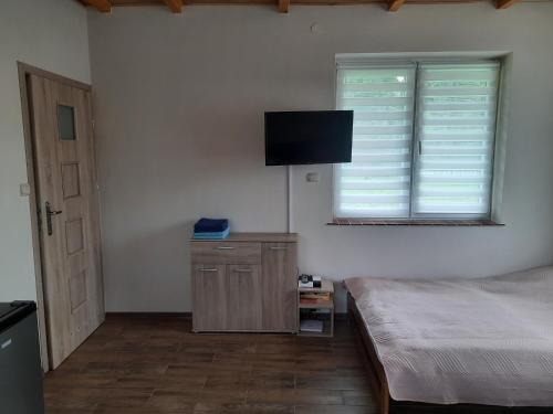 下乌斯奇基Brzoskwiniowy Domek Ustrzyki Dolne的一间卧室配有一张床和一台平面电视