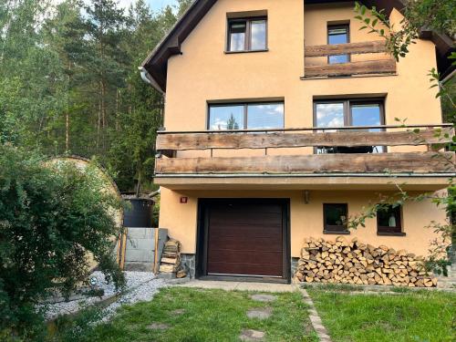ChyšeChata s panoramatickou saunou的一座房子,里面设有车库和一堆木柴