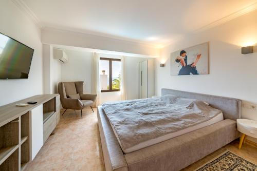 Badia GranFerienhaus Casa Kristel的一间卧室配有一张床、一台电视和一把椅子
