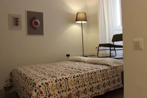 罗马Colosseo Living Suites的一间卧室配有一张床、一盏灯和一把椅子