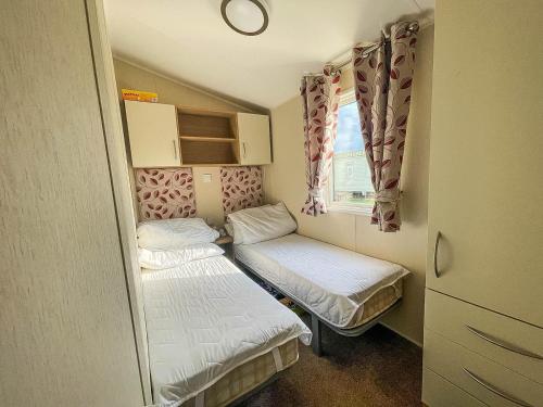 滨海克拉克顿Caravan With Decking And Free Wifi At Seawick Holiday Park Ref 27214sw的小房间设有两张床和窗户