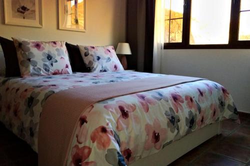 TinguatónCasa Guiguan的一间卧室配有一张带花卉床罩的床和窗户。