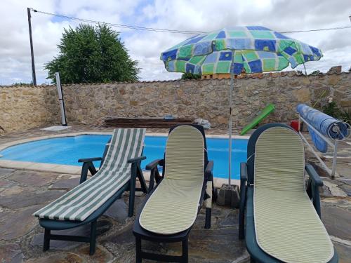 Mata de QuintanarEl Refugio de la Esquina的游泳池旁的桌椅和遮阳伞
