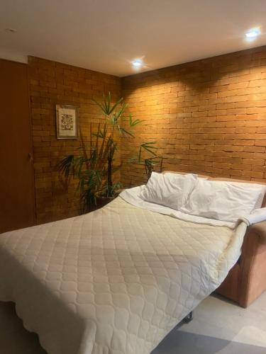 彼得罗波利斯Loft da Beth na serra的卧室配有白色的砖墙床