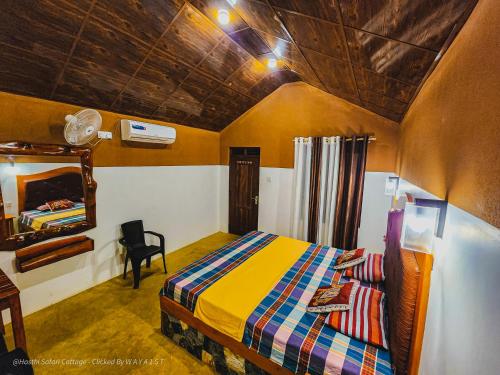 达瓦拉维Hasthi Safari Cottage的一间卧室配有一张床、镜子和椅子