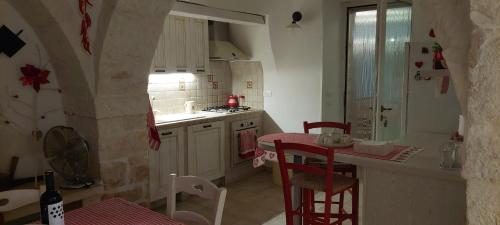 马丁纳弗兰卡Trullo Vito in Valle D itria con piscina的厨房配有柜台和红色的桌椅