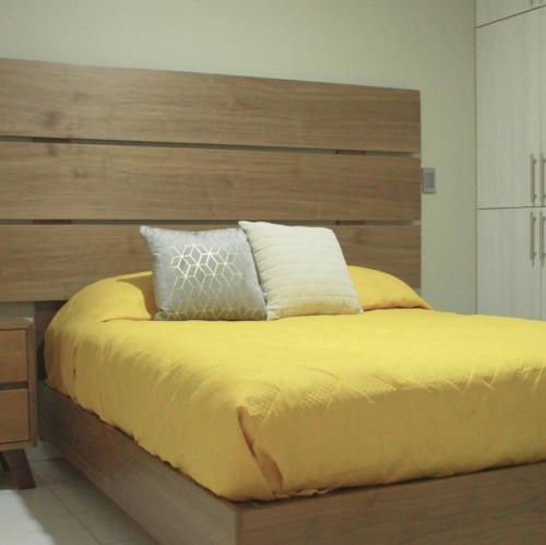 乌鲁阿潘San Juan Apartament的一间卧室配有一张大床和木制床头板