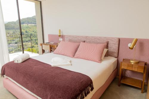 辛方伊什QUINTA ALTO DO RIO的一间卧室配有带粉红色枕头的床和窗户。