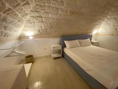曼弗雷多尼亚A Casa del Console apartment的一间小卧室,配有一张床和石墙