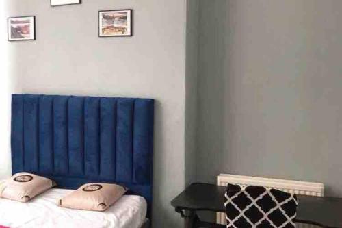 爱丁堡Grange Lone entire apartment with two double beds的一间设有一张蓝色床头板和一张桌子的房间