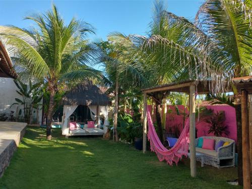 卡诺格布拉达Vila Beija-flor的庭院中带吊床和棕榈树的度假胜地