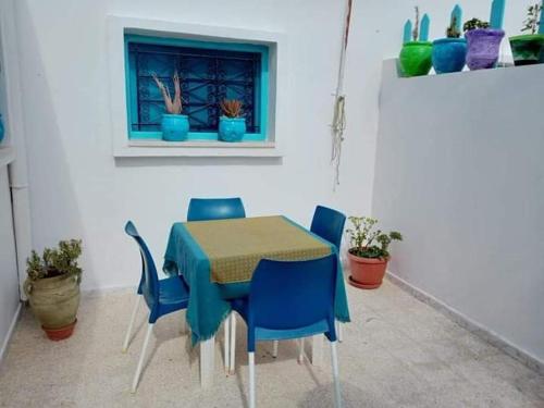 米多恩Bungalow Djerbien的一张桌子和椅子、一张蓝色的桌子和一个窗口