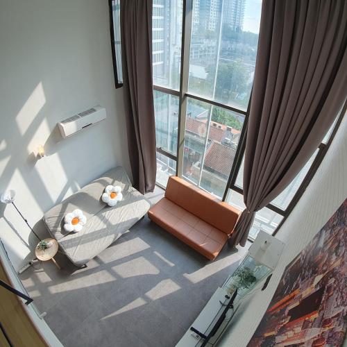 卡邦吉兰My Houze - Empire Damansara Duplex的窗户前的一张沙发和一把椅子