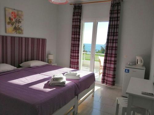 埃费奥纳斯Vrachos Pension的一间卧室配有一张带紫色毯子的床和窗户。