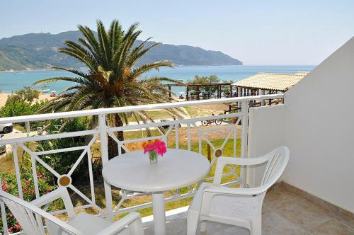 埃费奥纳斯Vrachos Pension的阳台上配有白色的桌椅,享有海景