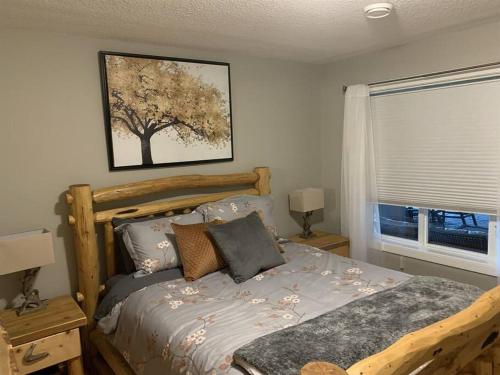 舍伍德帕克Dragonfly Inn Loft & Walkout Suites的卧室配有一张床铺,墙上挂着一幅树景