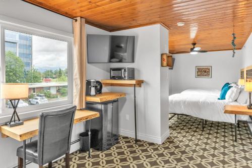 安克雷奇Highliner Hotel - Deluxe Double Queen with Mountain View的客房设有床、书桌和窗户。