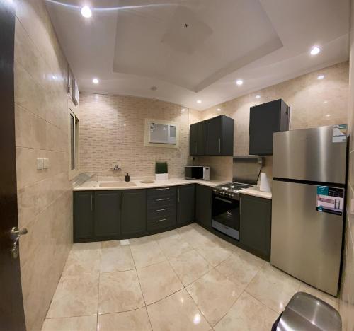 麦加2 Bedrooms Apartment in Makkah的厨房配有黑色橱柜和不锈钢冰箱