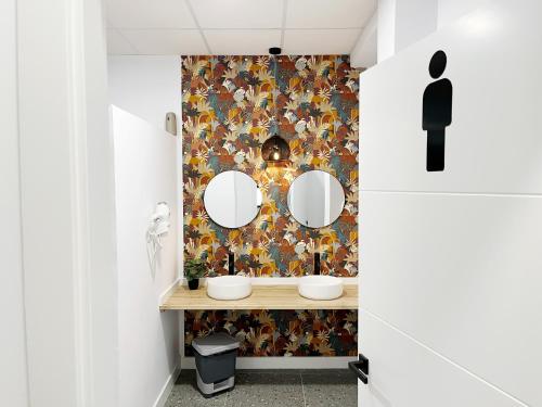 图伊A TROITA HOSTeL的浴室设有两面镜子和花卉壁纸