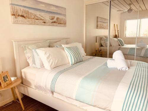 黄金海岸Cooly Coastal Escape walk to beach & shops的白色的床、白色枕头和镜子