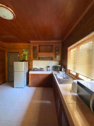 湄南海滩班拉加河内别墅酒店的厨房配有木制橱柜和白色冰箱。