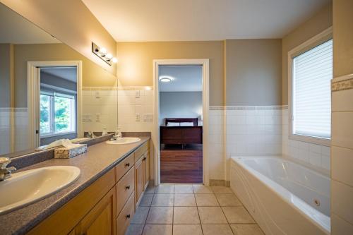 皮奇兰First Estate Winery的浴室配有两个盥洗盆、浴缸和浴缸。