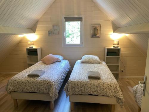索米尔Les Chalets de SAUMUR, Piscine & Parc boisé, 100m du CadreNoir的一间卧室设有两张床和窗户。
