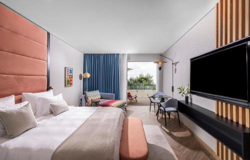 内韦伊兰Almond Hotel - Adults only的配有一张床和一台平面电视的酒店客房