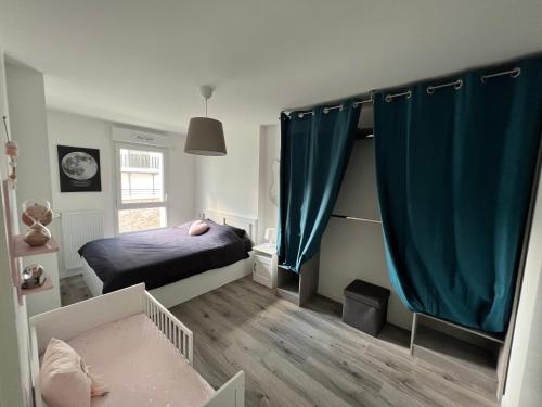 普瓦西Appartement avec son jardin d’hiver的一间小卧室,配有床和蓝色窗帘