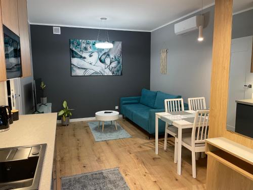 马佐夫舍地区新庄园Caroline Jacuzzi Apartments的客厅配有蓝色的沙发和桌子