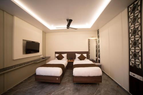 卡基纳达MURALI KRISHNA APART HOTEL的配有电视的房间和房间,设有两张床