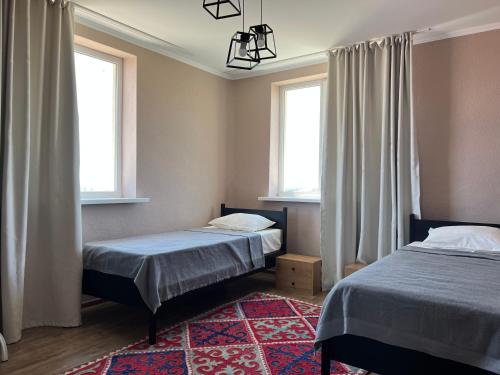乔尔蓬阿塔Guest house Hygge的两张位于带两扇窗户和地毯的客房内的床铺
