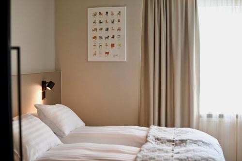 雷克雅未克Hotel Local 101的一间卧室配有一张带白色床单的床和一扇窗户。