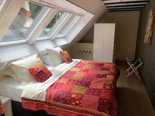 兹沃勒Landgoedhuisje de Blije Uil的一间卧室配有一张带被子的床和两个窗户