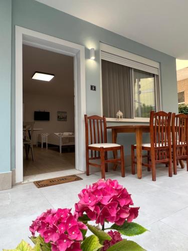 都拉斯Art Studio Apartments Durrës的客厅配有桌椅和粉红色的鲜花