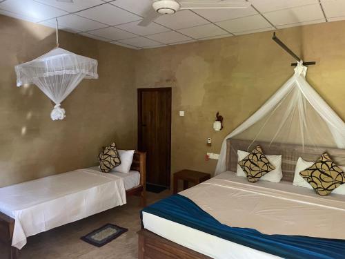 锡吉里亚Shan Mango Homestay的卧室配有两张床,墙上挂有蚊帐。