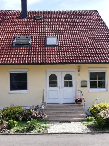 于伯林根Ferienwohnung am Bodensee mit 3 Schlafzimmer über 2 Etage mit kleine Balkon bis 7 Personen的一座红色屋顶和白色门的房子