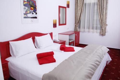 蒂米什瓦拉Hotel Exclusiv的卧室配有白色的床和红色枕头