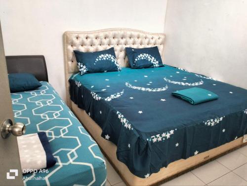 话毛生Homestay Saujana Harmoni D'Petron的一间卧室配有两张带蓝白色床单的床