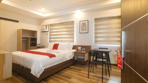 马尼拉RedDoorz Plus @ Bez Tower and Residences San Juan的一间卧室配有一张床和一张桌子及椅子