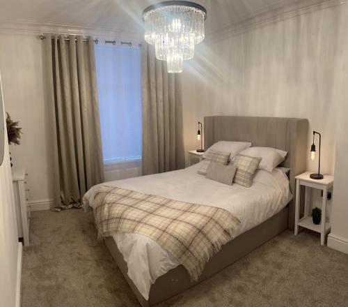 锡厄姆Coastal Apartments No 2的一间卧室配有一张大床和一个吊灯。