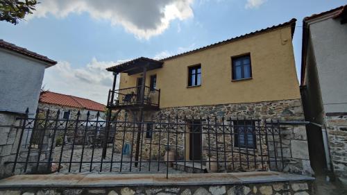 VávdhosThe Stone House in Halkidiki的前面有栅栏的建筑