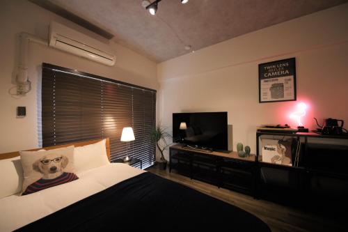 福冈goom Hotel Nakasu的一间卧室配有一张床和一台平面电视