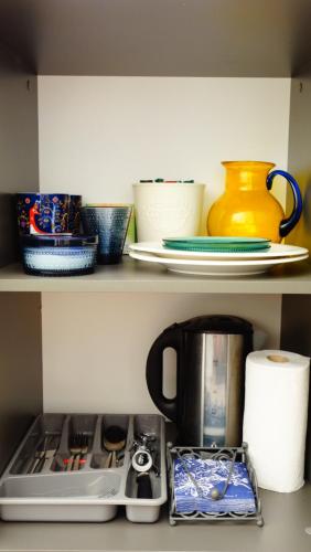 LiivaIntsu Royal Kadakametsa Glämp的一个带碗和杯子的厨房架和一个咖啡壶