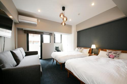福冈ZONK HOTEL Nakasu的酒店客房,设有两张床和一张沙发