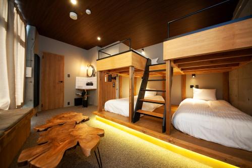 福冈ZONK HOTEL Tenjin-Watanabedori的一间卧室设有两张双层床和一张桌子