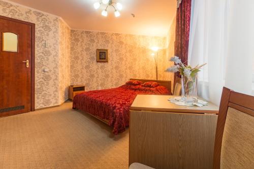 特鲁斯卡韦茨Hotel Premyer的一间卧室配有一张带红色床罩和桌子的床。