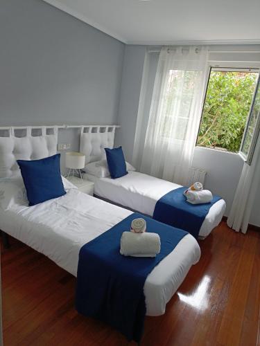 乌迪亚莱斯堡Paraíso Soleado: Piso con Terraza, Piscina y Garaje a 5 min de Playa的一间卧室配有两张带蓝白色床单的床